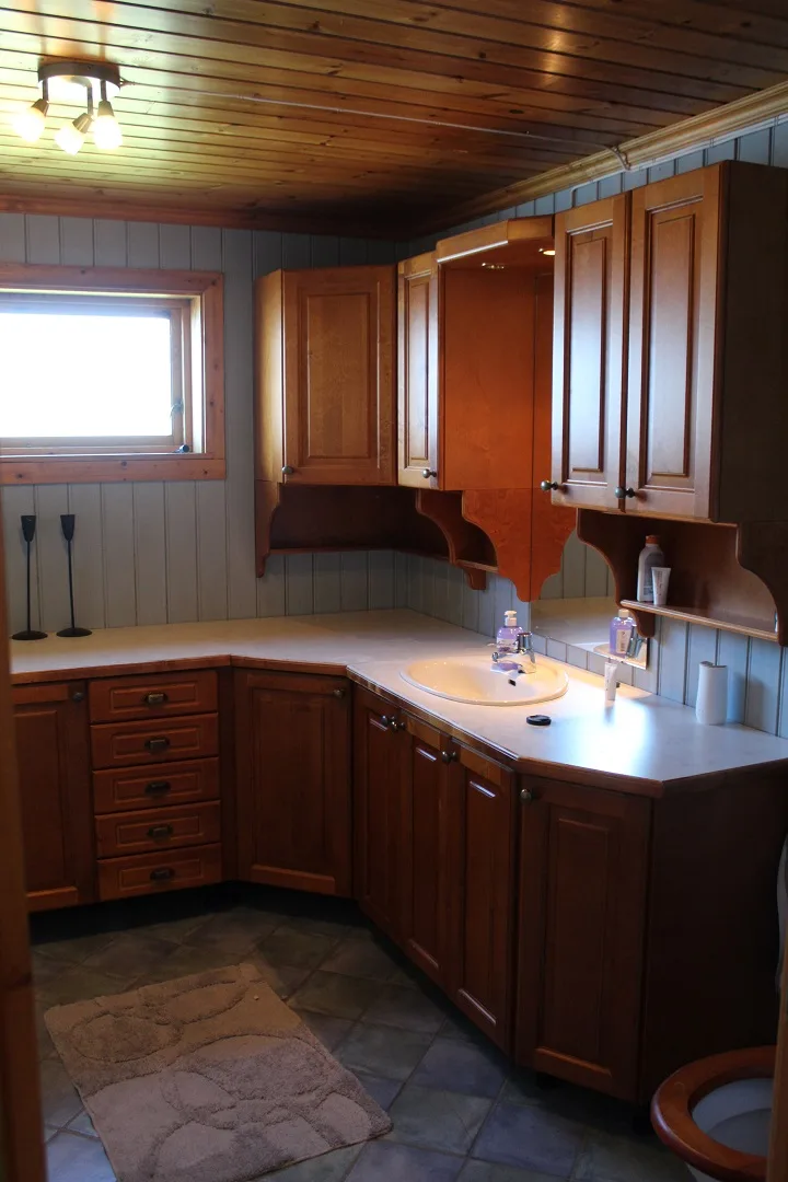 Un tocador de baño con gabinetes de madera oscura, un lavabo y una ventana.
