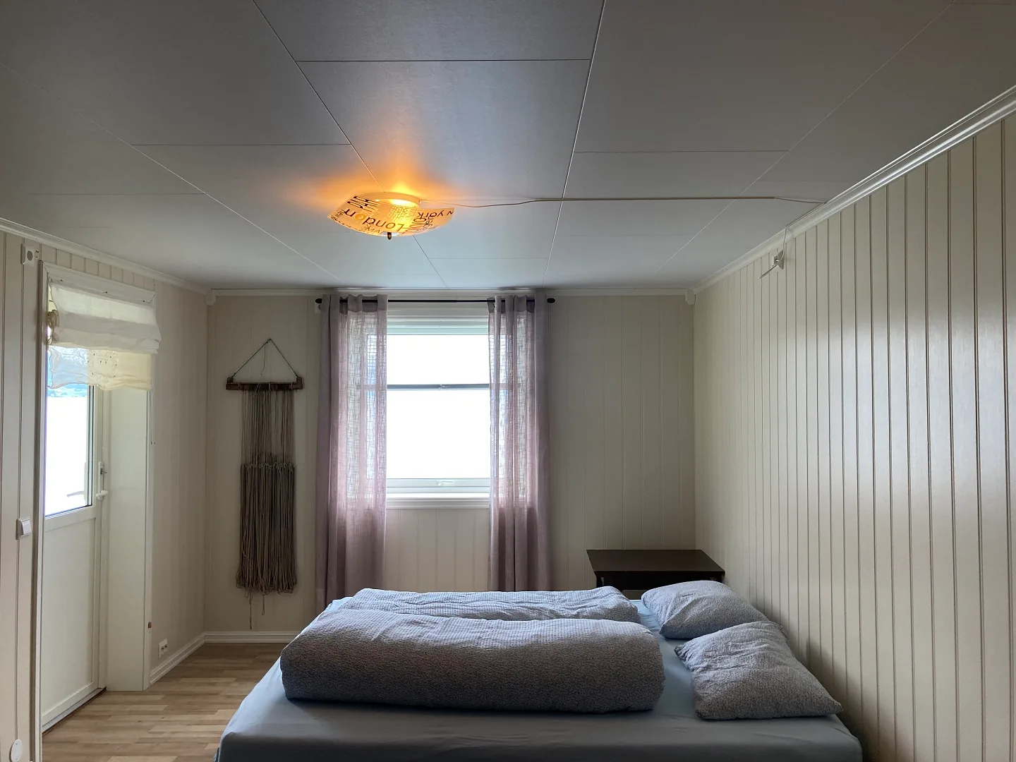 Dormitorio con una cama debajo de una ventana con cortinas.