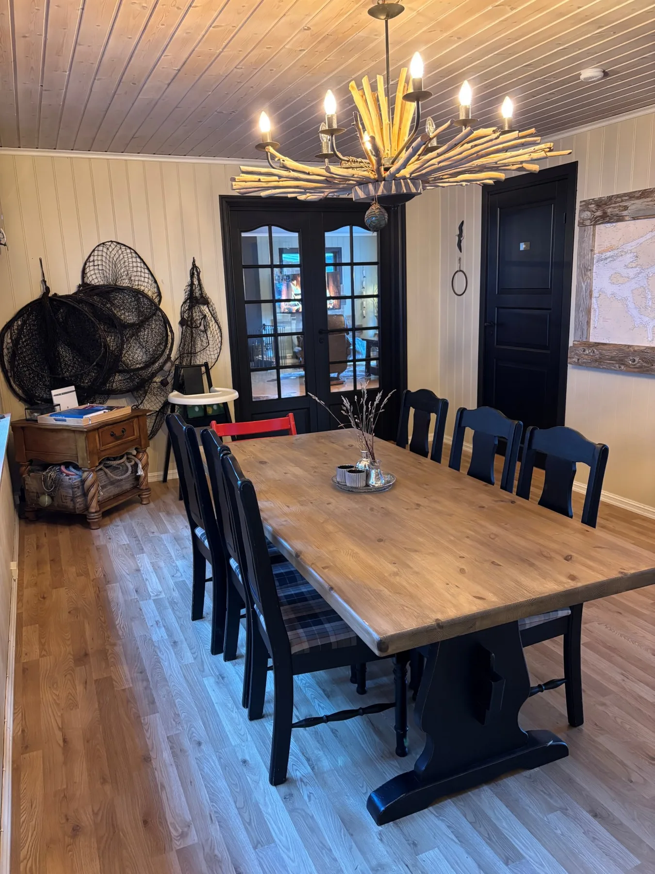 Comedor con una mesa larga de madera, sillas oscuras y una gran lámpara de araña.