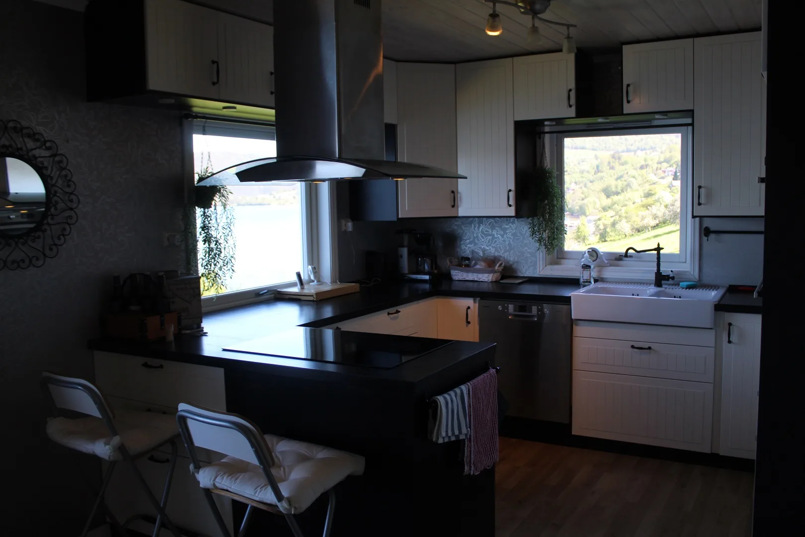 Una cocina con encimeras oscuras y un fregadero bajo una ventana.