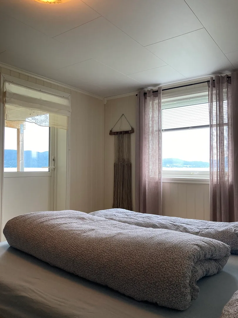 Un dormitorio con una cama baja y ventanas con vistas al agua.