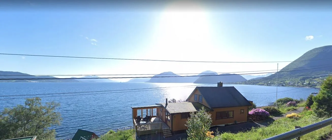 Una casa junto a un lago, con montañas visibles al otro lado del agua.