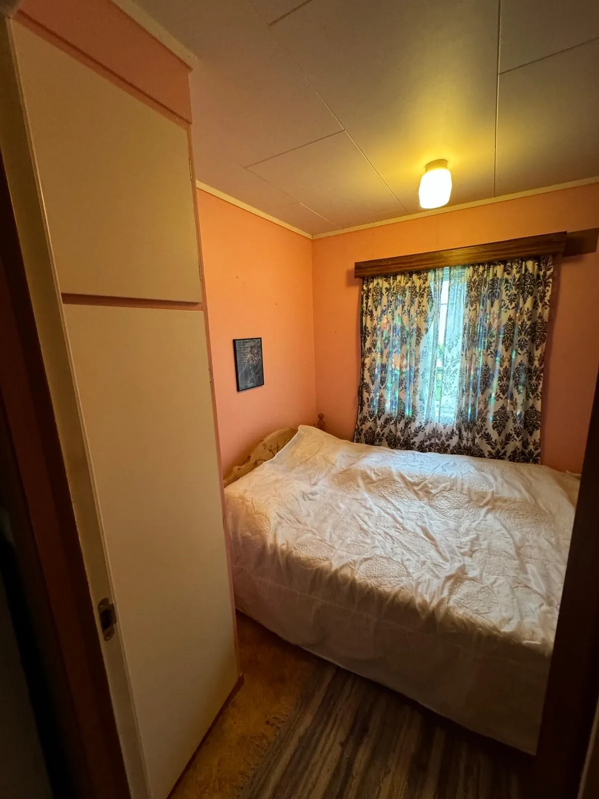 Un dormitorio con una cama bajo una ventana con cortinas.