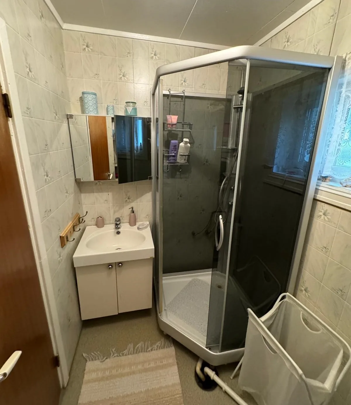 Un baño alicatado con lavabo, armario con espejo y ducha de vidrio.