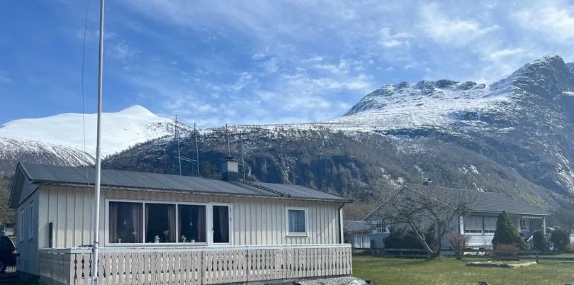 Un edificio bajo se alza ante una cordillera nevada.