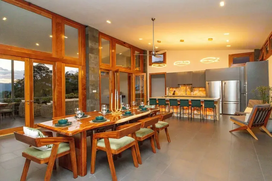 Un comedor con una larga mesa de madera junto a grandes ventanas.