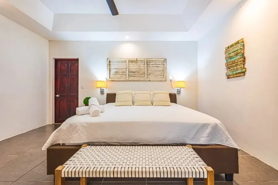 A bedroom with a large bed and a bench at the foot.