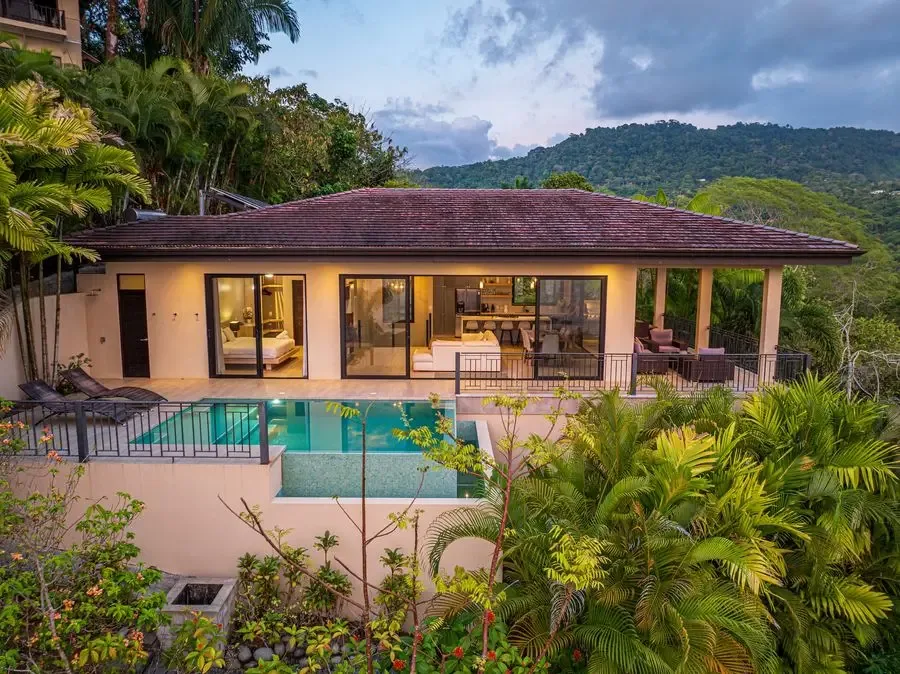 A house with a swimming pool, surrounded by tropical greenery.