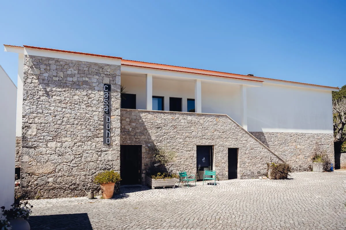 Espacio representativo del hotel: Un edificio con fachada de piedra, patio pavimentado y asientos al aire libre.