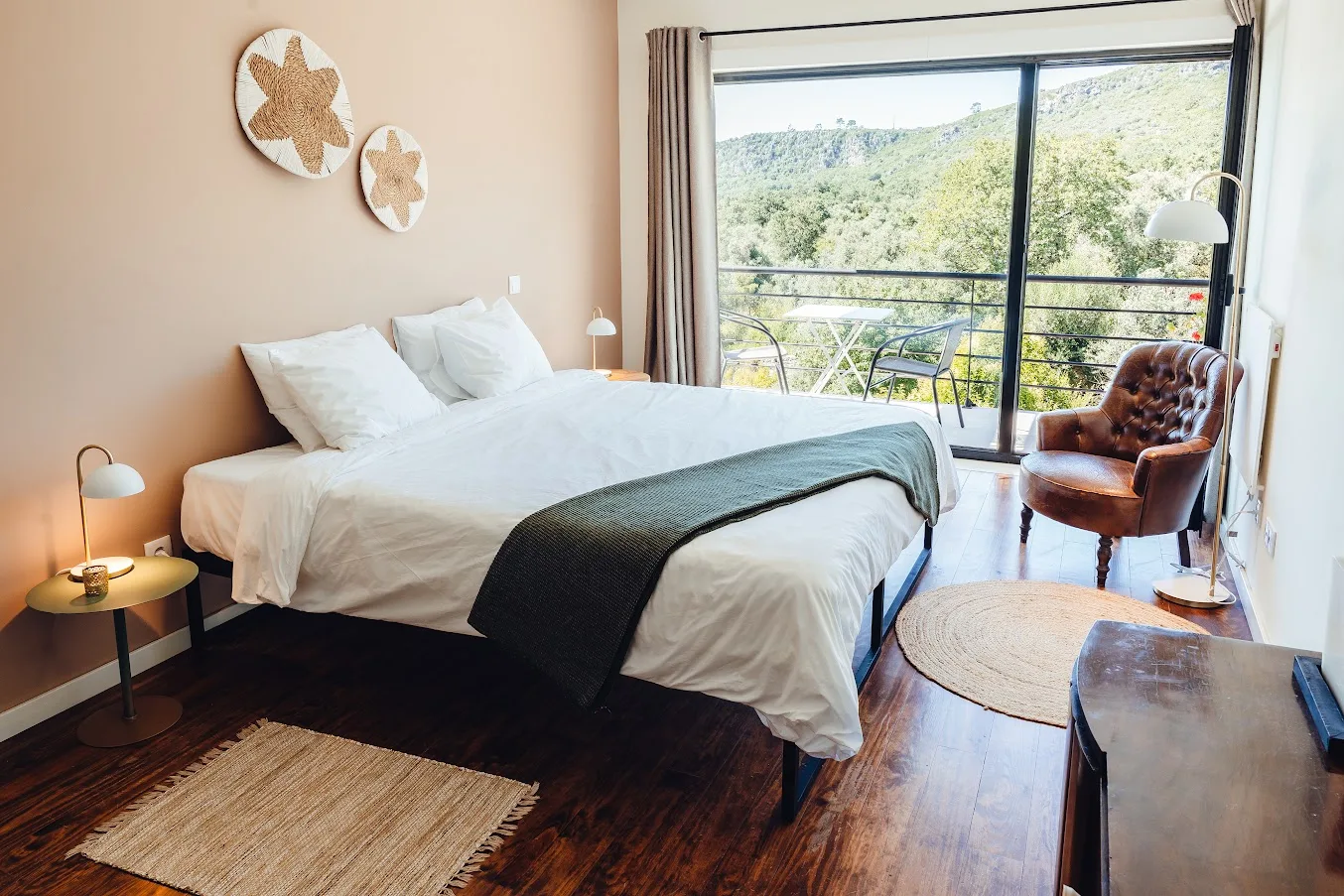 Espacio representativo del hotel: Un dormitorio luminoso con una cama tendida y una gran ventana con vistas a la vegetación.