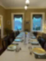 Espacio representativo del hotel: Un comedor con una mesa larga preparada con vajilla y asientos.