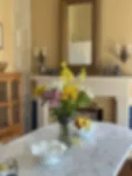 Espacio representativo del hotel: Comedor con una mesa, flores y un espejo sobre la repisa.