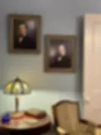 Representative hotel space: A sitting area with framed pictures, a table lamp, and a chair.
