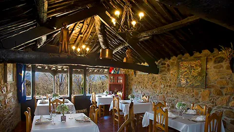 Espacio representativo del hotel: Un comedor rústico con mesas preparadas bajo vigas de madera expuestas.