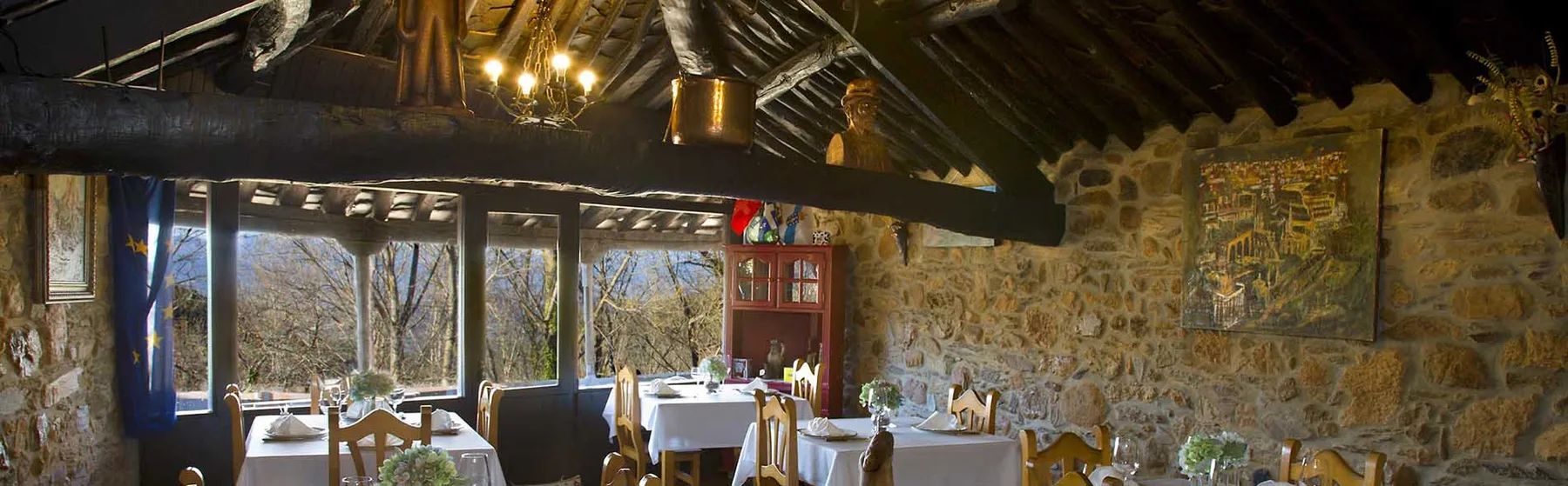 Espacio representativo del hotel: Un comedor rústico con mesas junto a grandes ventanas.