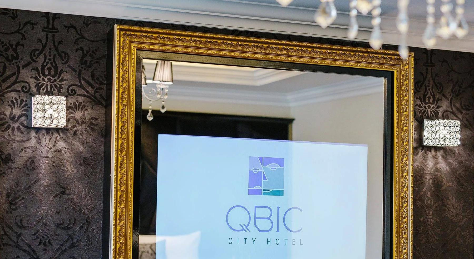 Representative hotel space: A hotel room mirror with decorative lighting and a hotel logo visible in the reflection.