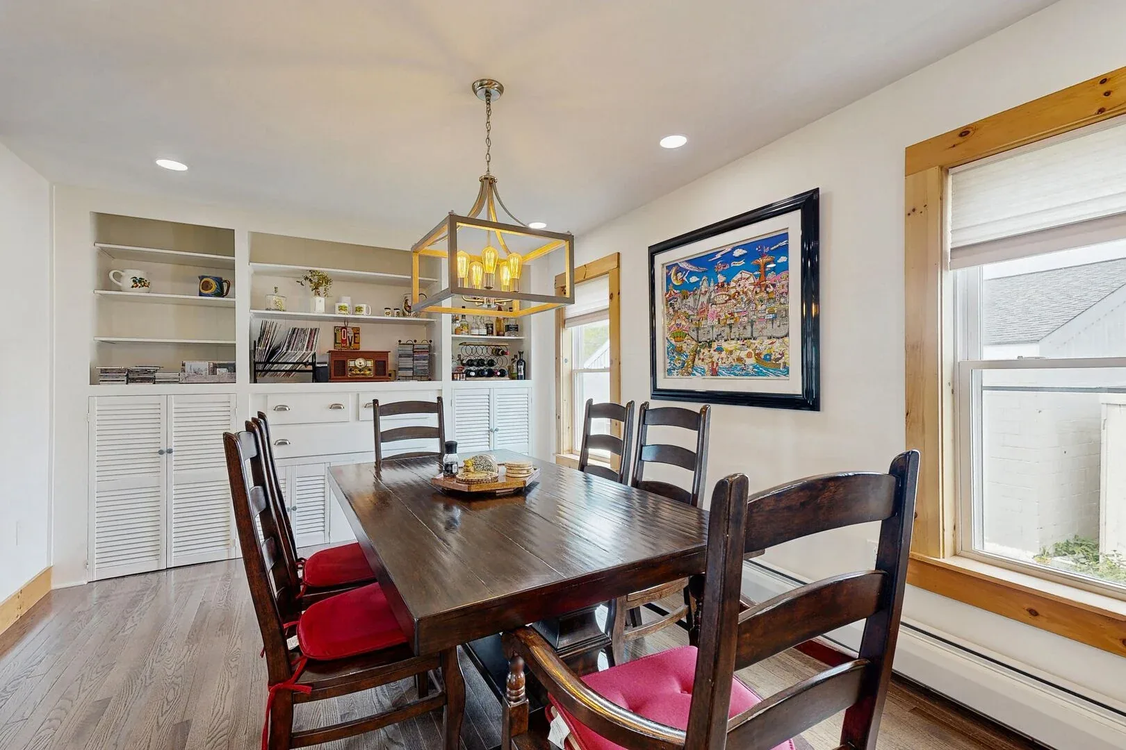 A dining area with a wooden table and built-in shelving along the wall.