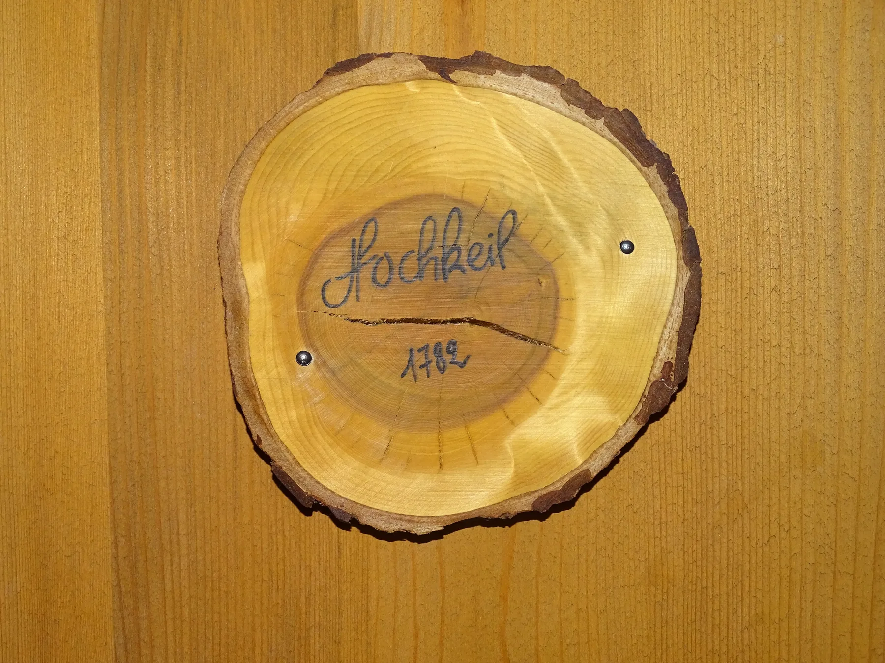 A wooden wall displays a round slice of wood with handwritten lettering.