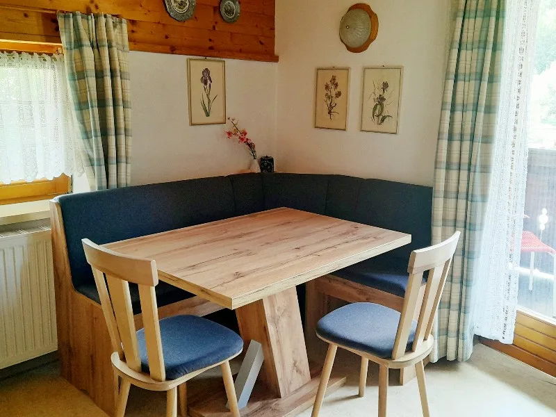 A dining nook with a wooden table, chairs, and a built-in bench.