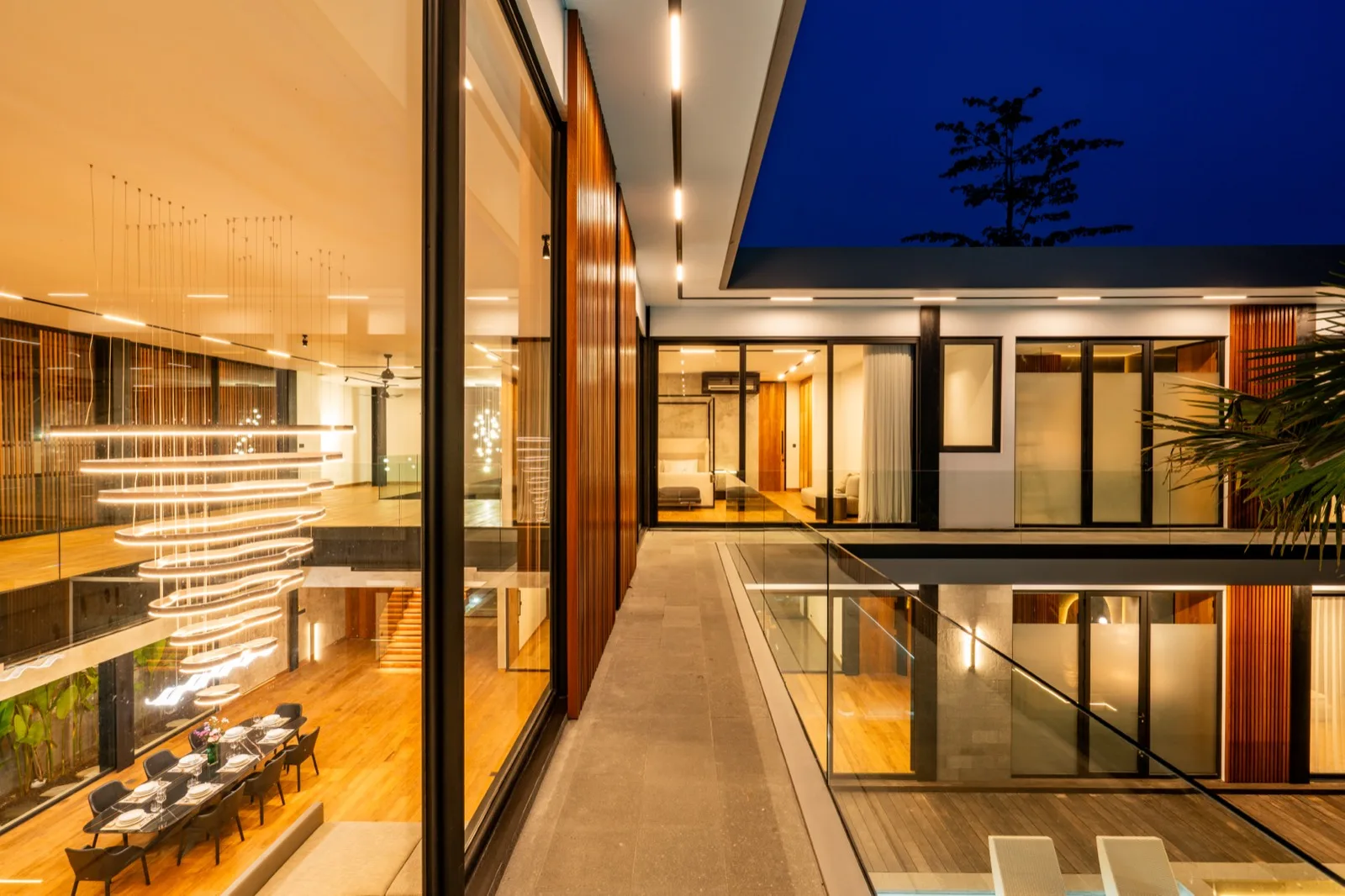 A modern glass-walled interior opens onto a covered walkway beside a reflecting pool.
