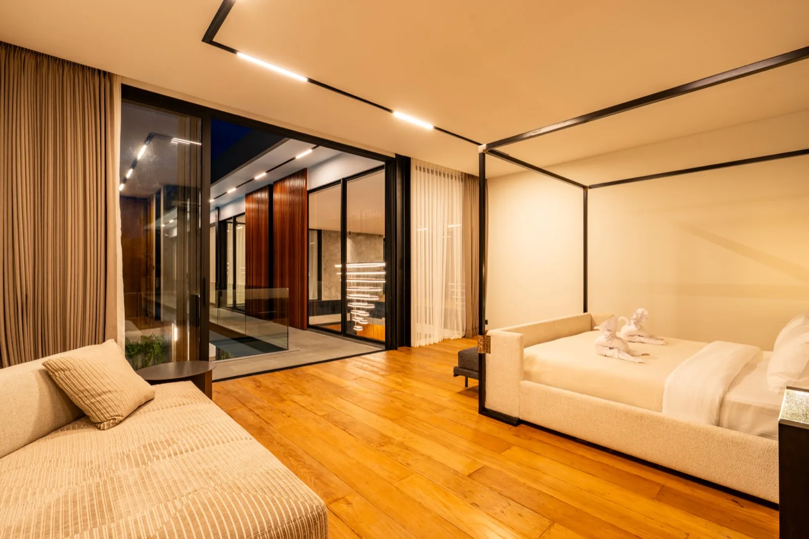 Un dormitorio moderno y cálido con una cama y asientos junto a ventanales.