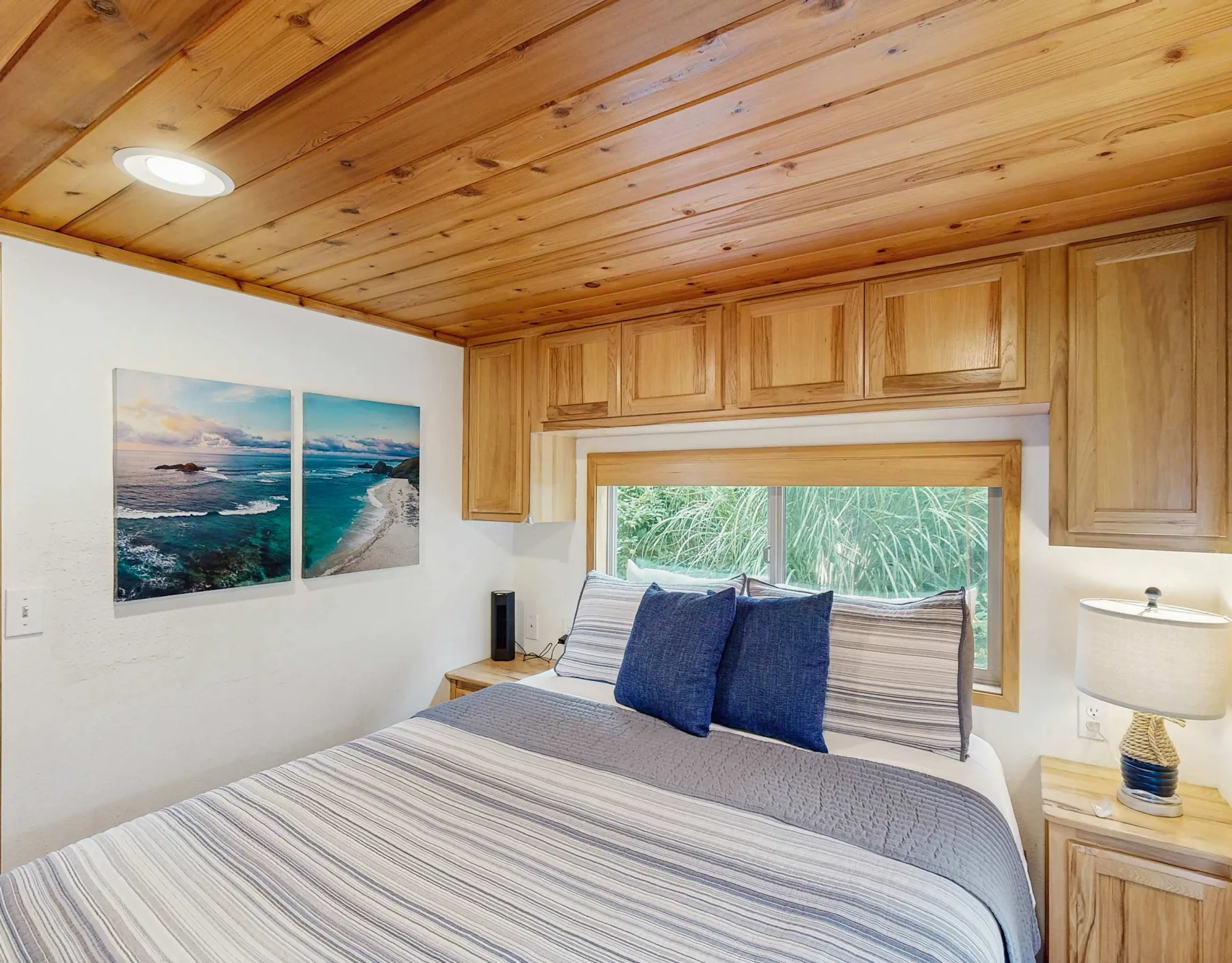 Un dormitorio con una cama a rayas bajo un techo y armarios de madera.