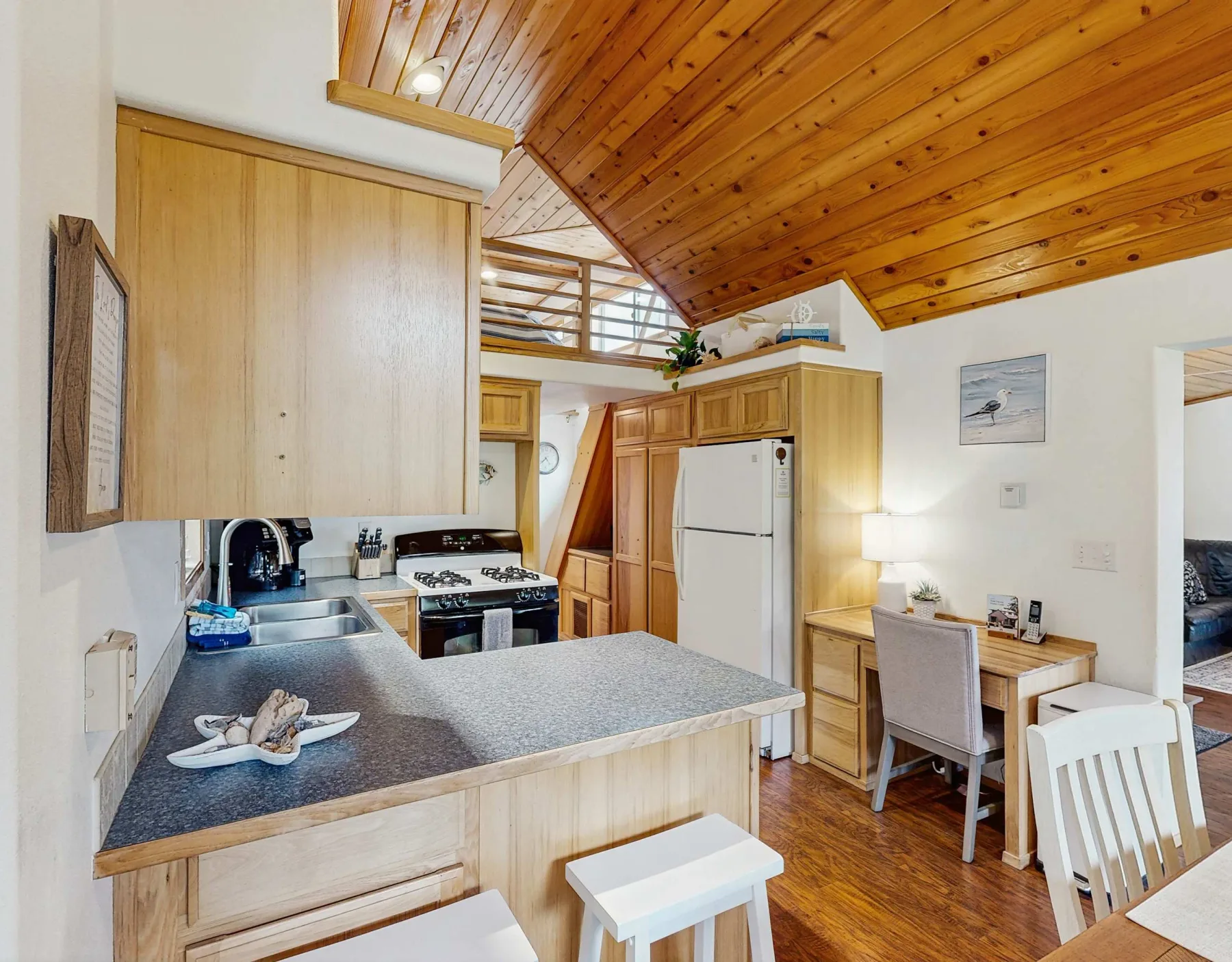 Cocina y comedor con una encimera, electrodomésticos y un techo inclinado de madera.