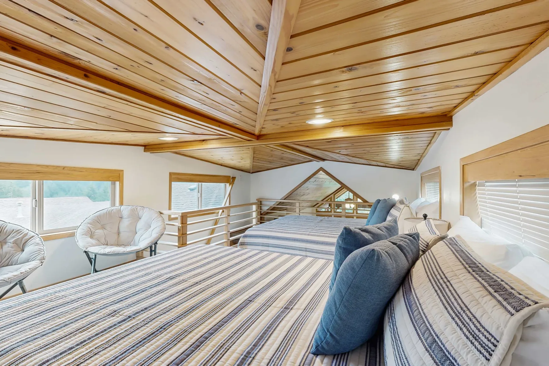 Una zona de descanso en un altillo con ropa de cama a rayas y techo de madera.
