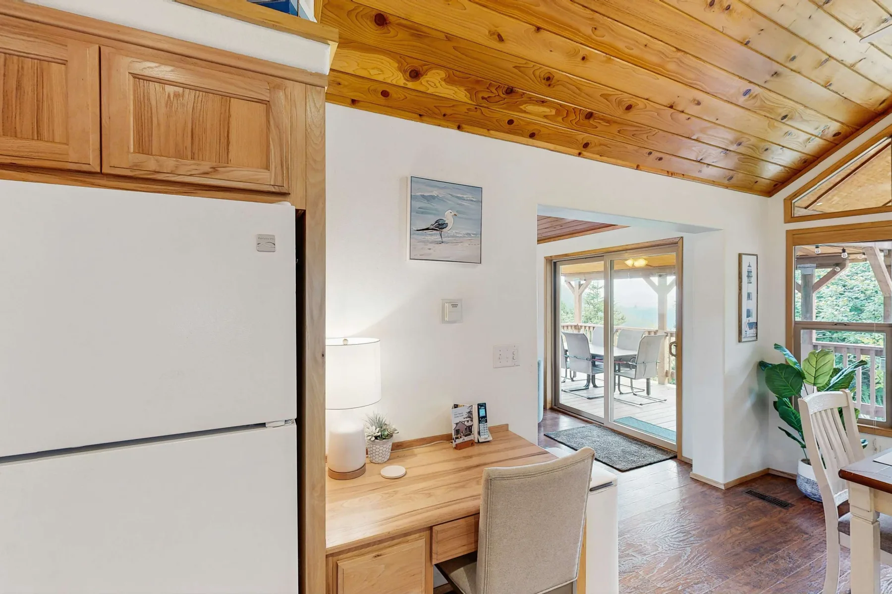 Un comedor y espacio de trabajo luminoso, con muebles de madera y ventanas que dan a un patio.