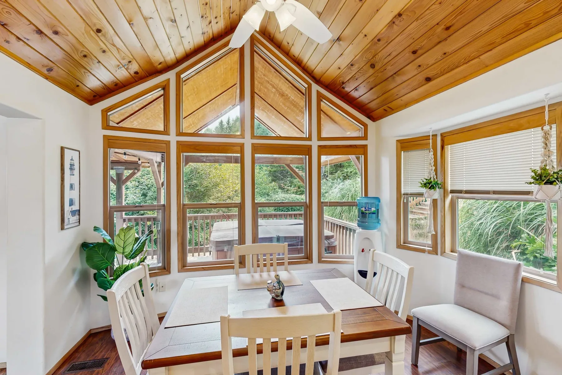 Un comedor luminoso con una mesa de madera bajo un techo inclinado de madera y grandes ventanas.