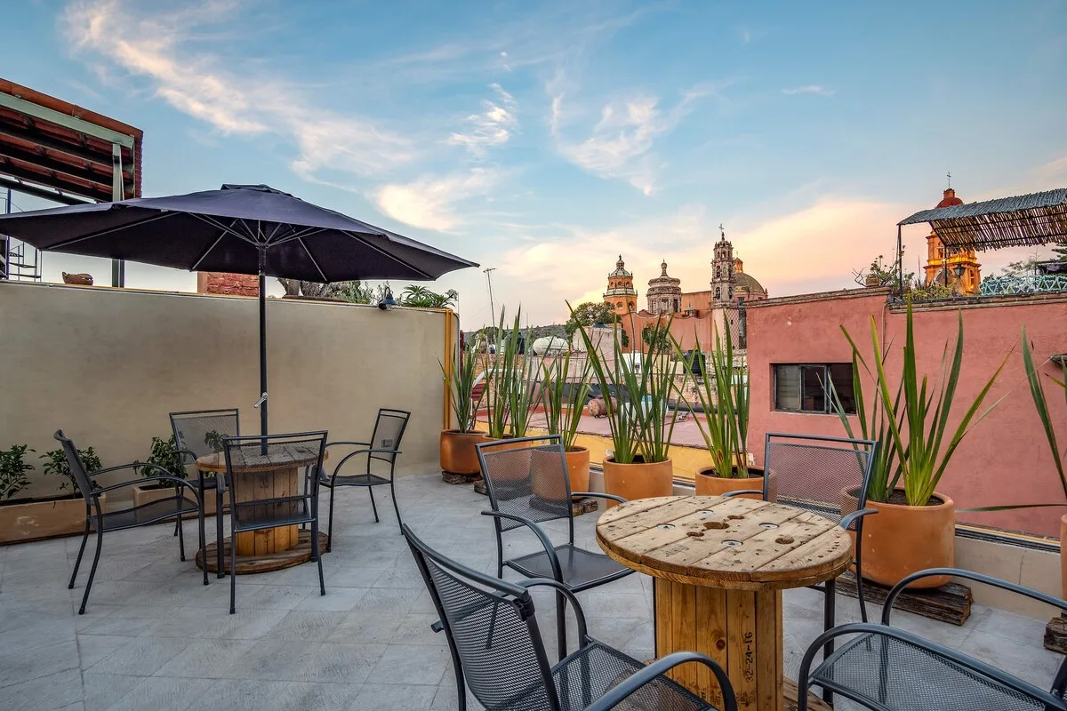 Zona común: Una terraza en la azotea tiene asientos al aire libre, plantas en macetas y vistas a edificios cercanos.