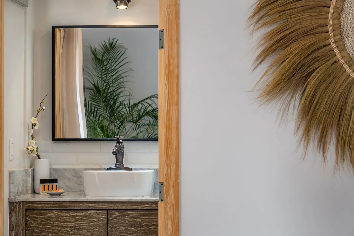 Un tocador de baño con lavabo sobre encimera y un espejo grande.