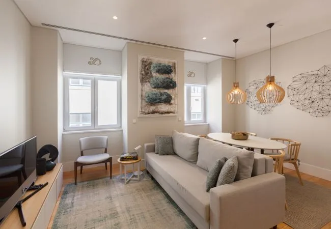 A bright living room with a sofa, dining table, and pendant lights.