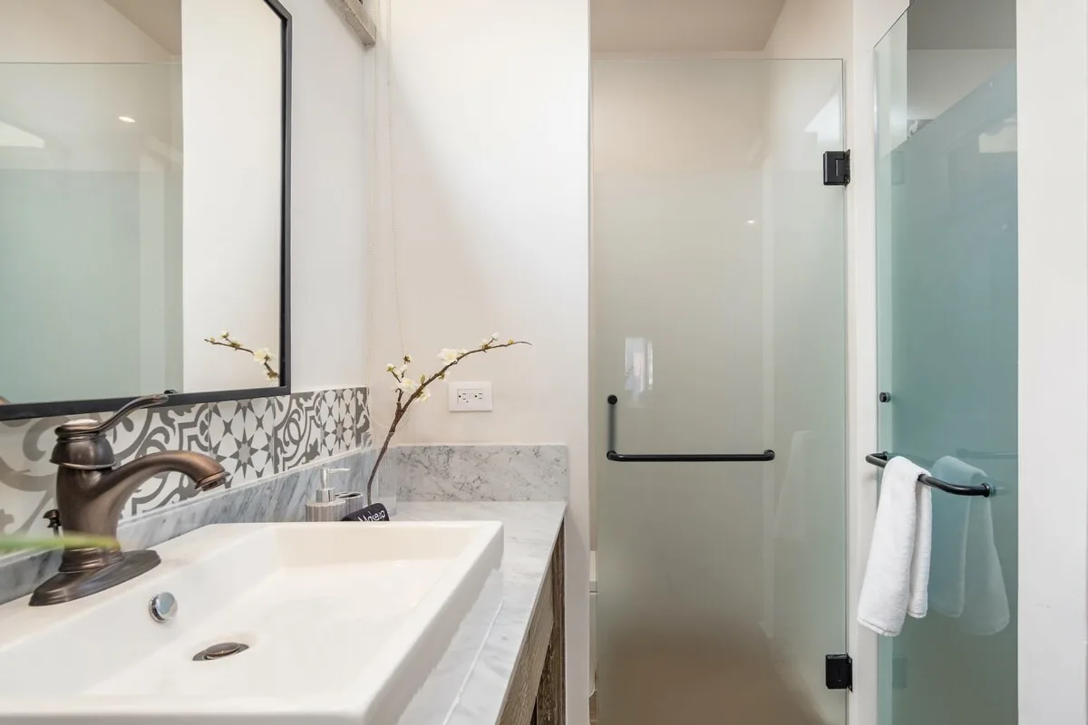 A bright bathroom with a white sink and a glass shower.