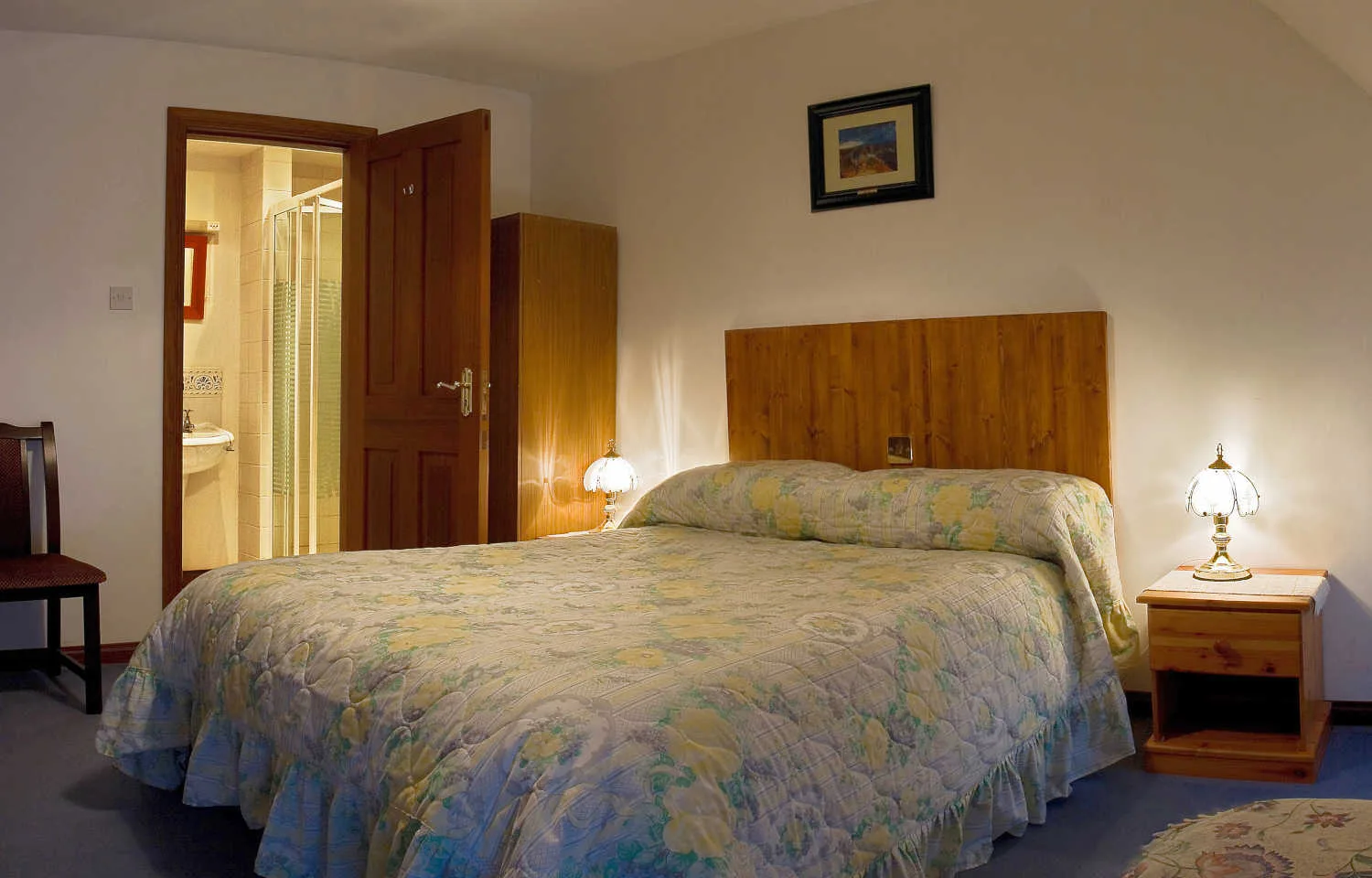 Espacio representativo del hotel: Un dormitorio con una cama doble, cabecero de madera y mesillas de noche.