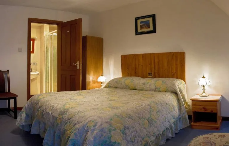 Espacio representativo del hotel: Un dormitorio con una cama grande, cabecero de madera y lámparas de mesilla.