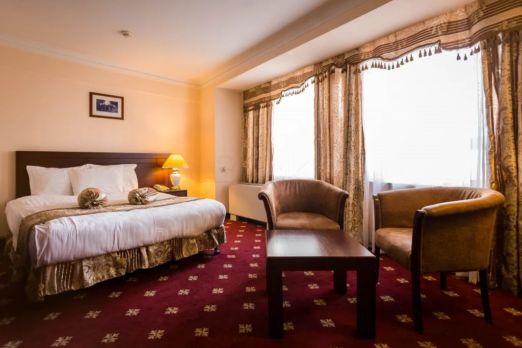 Espacio representativo del hotel: Dormitorio de hotel con una cama, sillones y una mesa junto a la ventana.