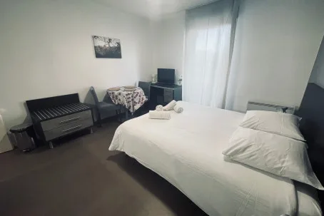 Un dormitorio con una cama tendida, una mesa pequeña y un televisor.