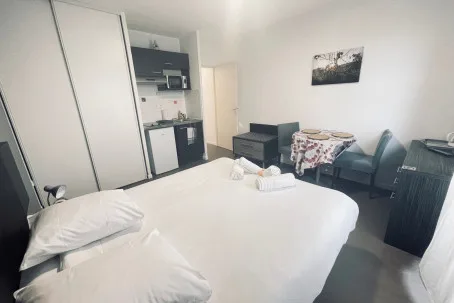 Dormitorio con cama, cocina pequeña y zona de comedor.