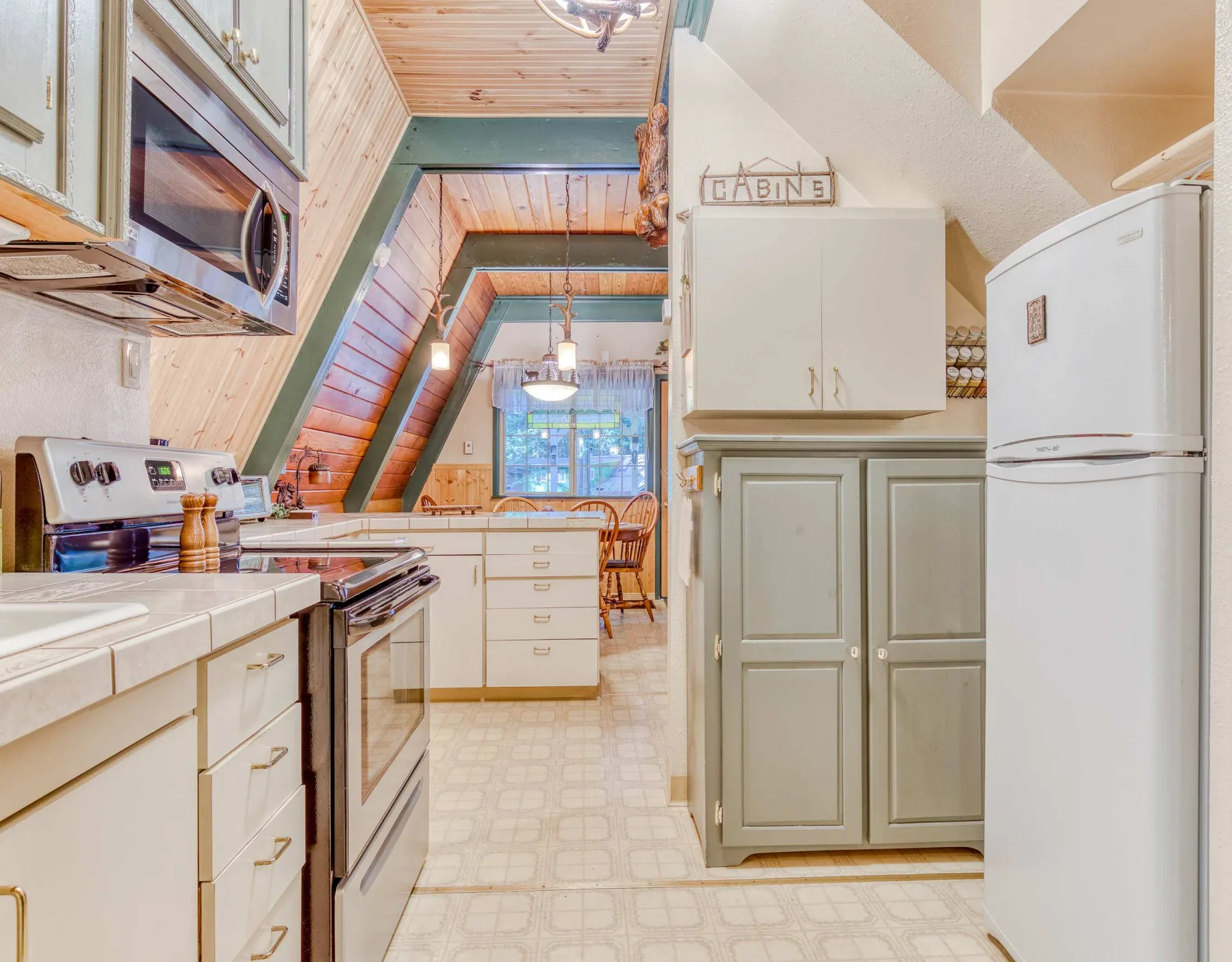 Una cocina con gabinetes claros, una estufa y un refrigerador.