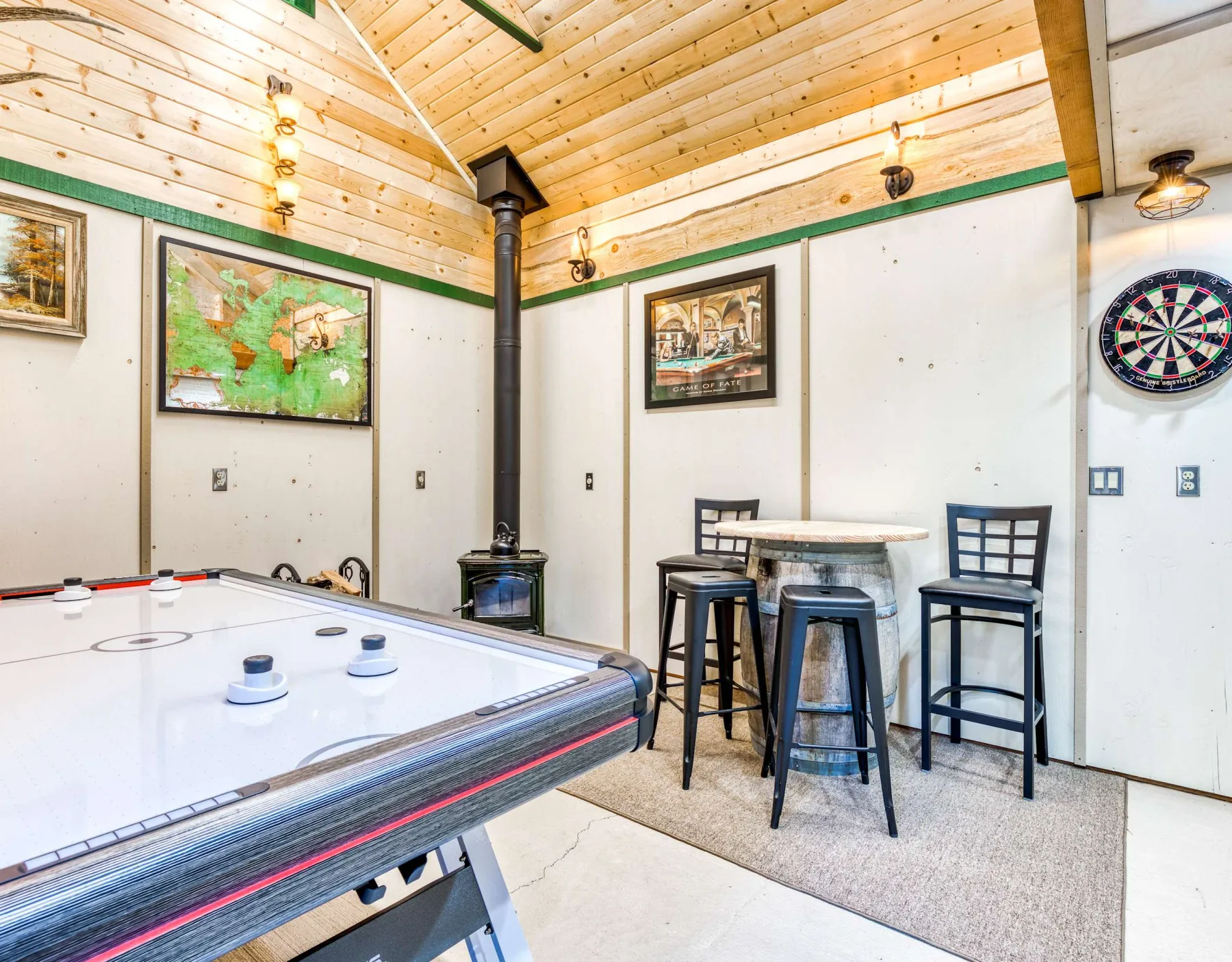 Una sala de juegos con una mesa de hockey de aire, asientos de bar y una diana.