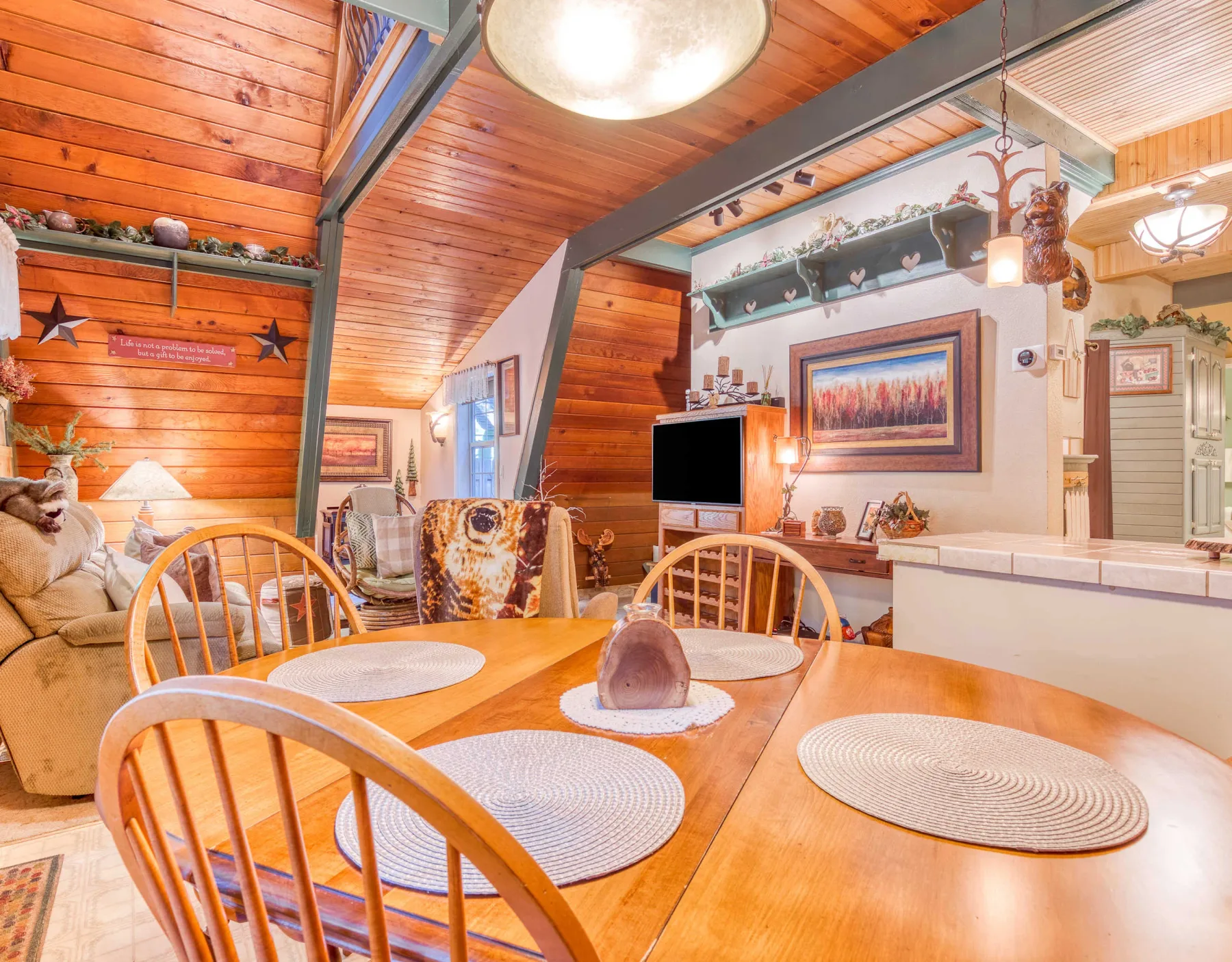 Un comedor con una mesa de madera y asientos junto a una sala de estar.