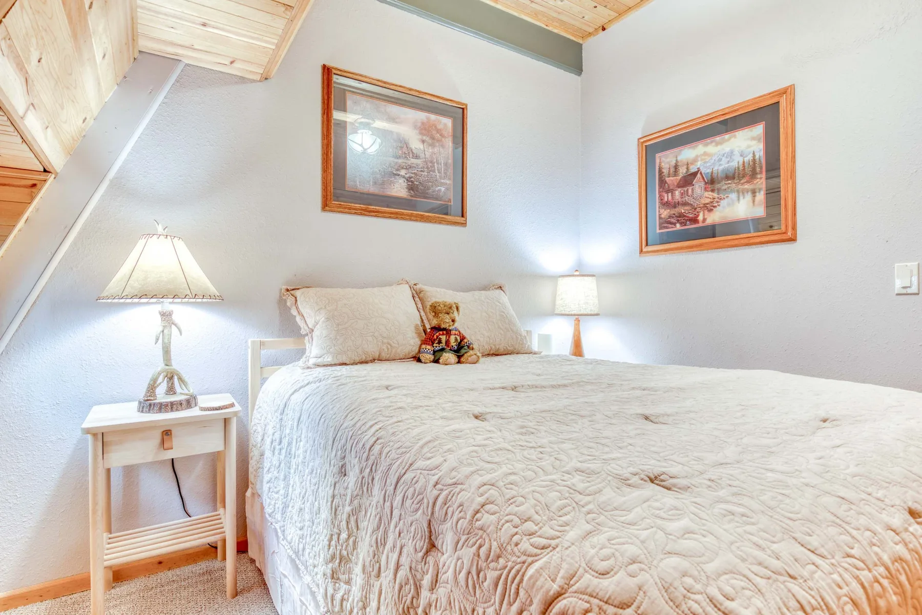 Un dormitorio con una cama grande, mesitas de noche y cuadros en las paredes.
