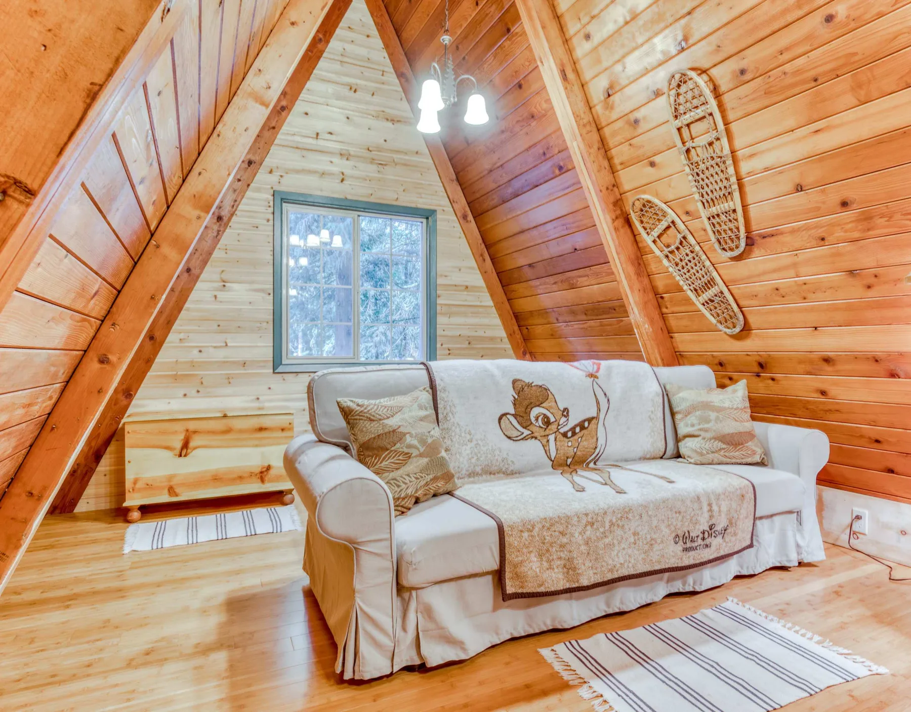 Una sala con paredes de madera y un sofá bajo un techo inclinado.