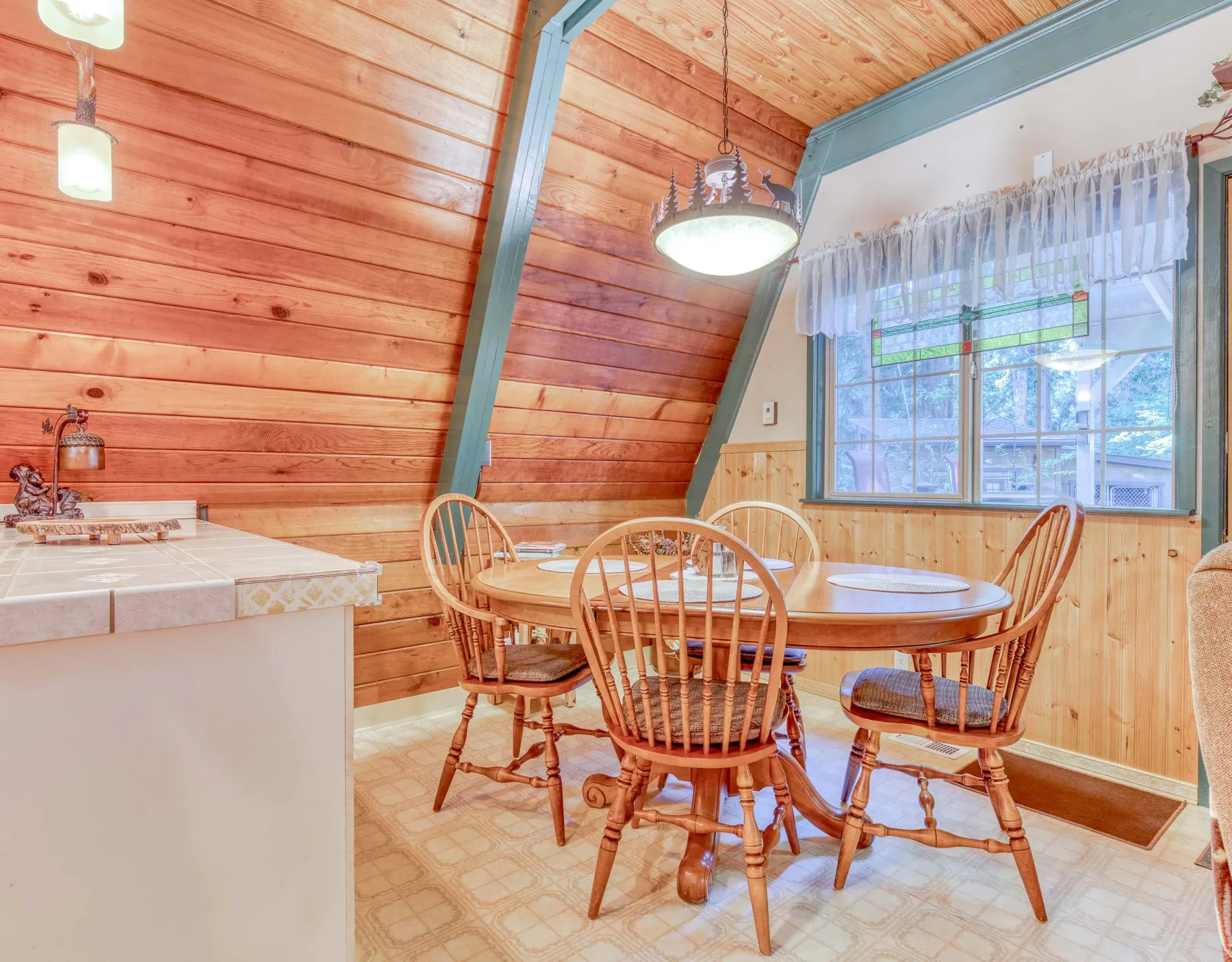 Comedor con una mesa de madera y sillas junto a una ventana grande.