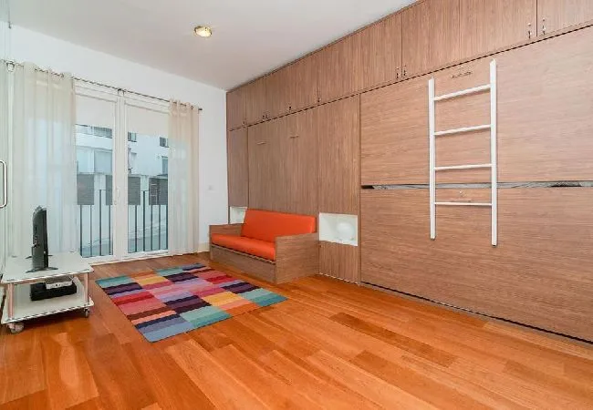 Una sala de estar con un sofá naranja y una alfombra colorida.