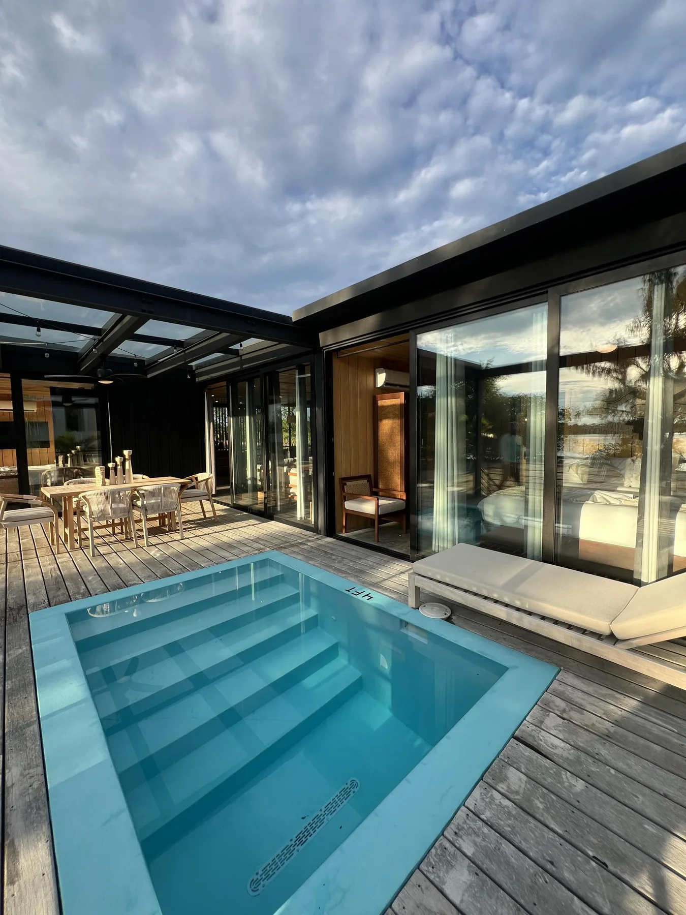 A courtyard pool sits beside glass walls and an outdoor dining area.