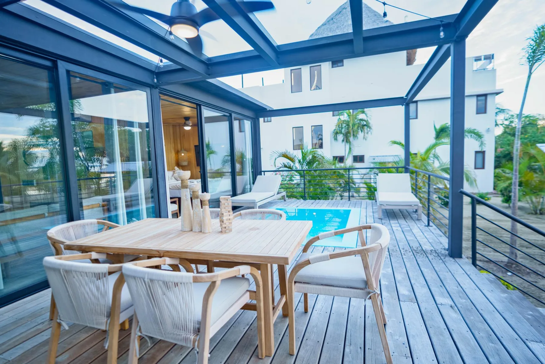 An outdoor dining terrace with a table, seating, and a small pool.