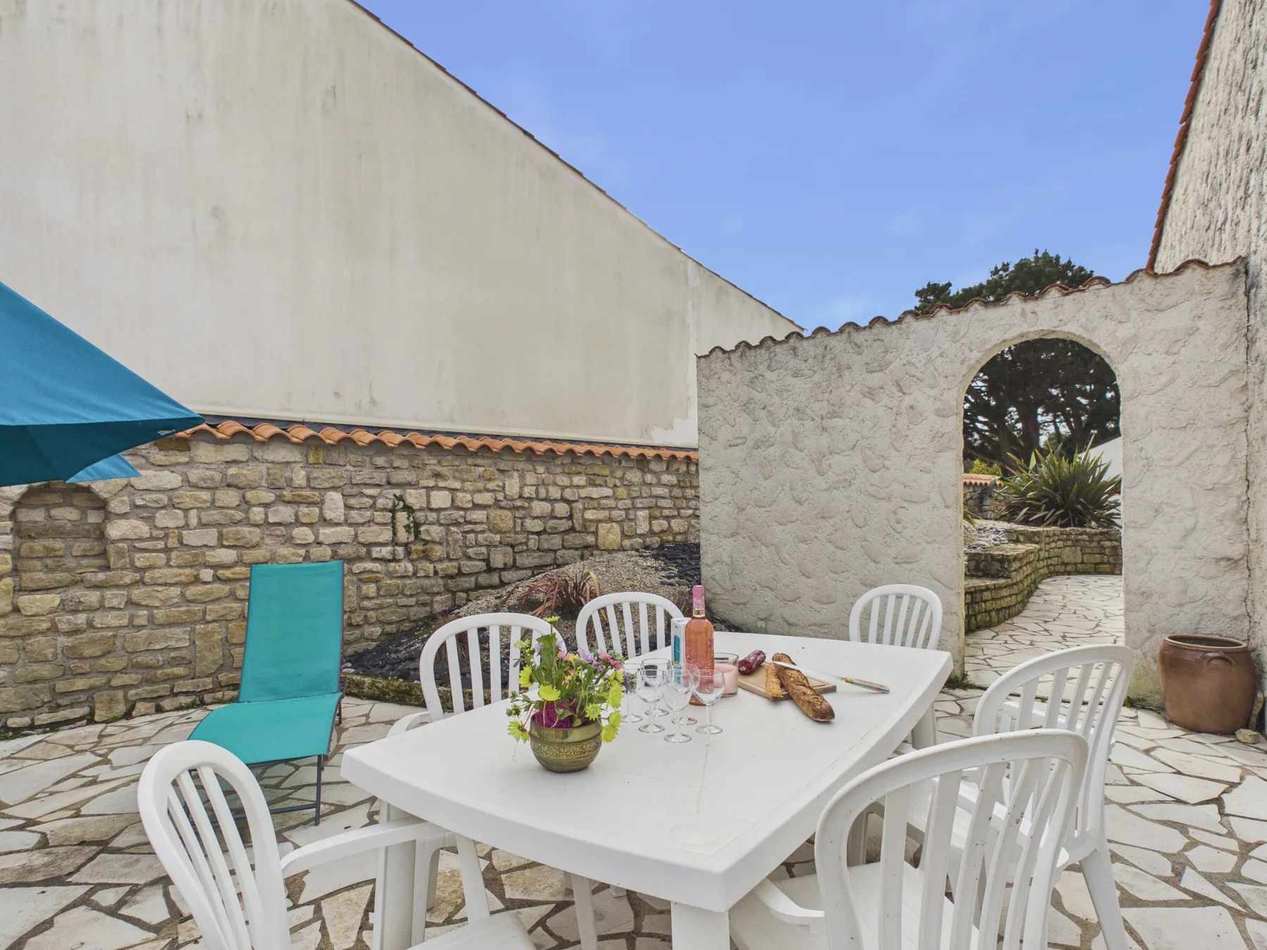 A stone courtyard dining area with a white table and chairs.