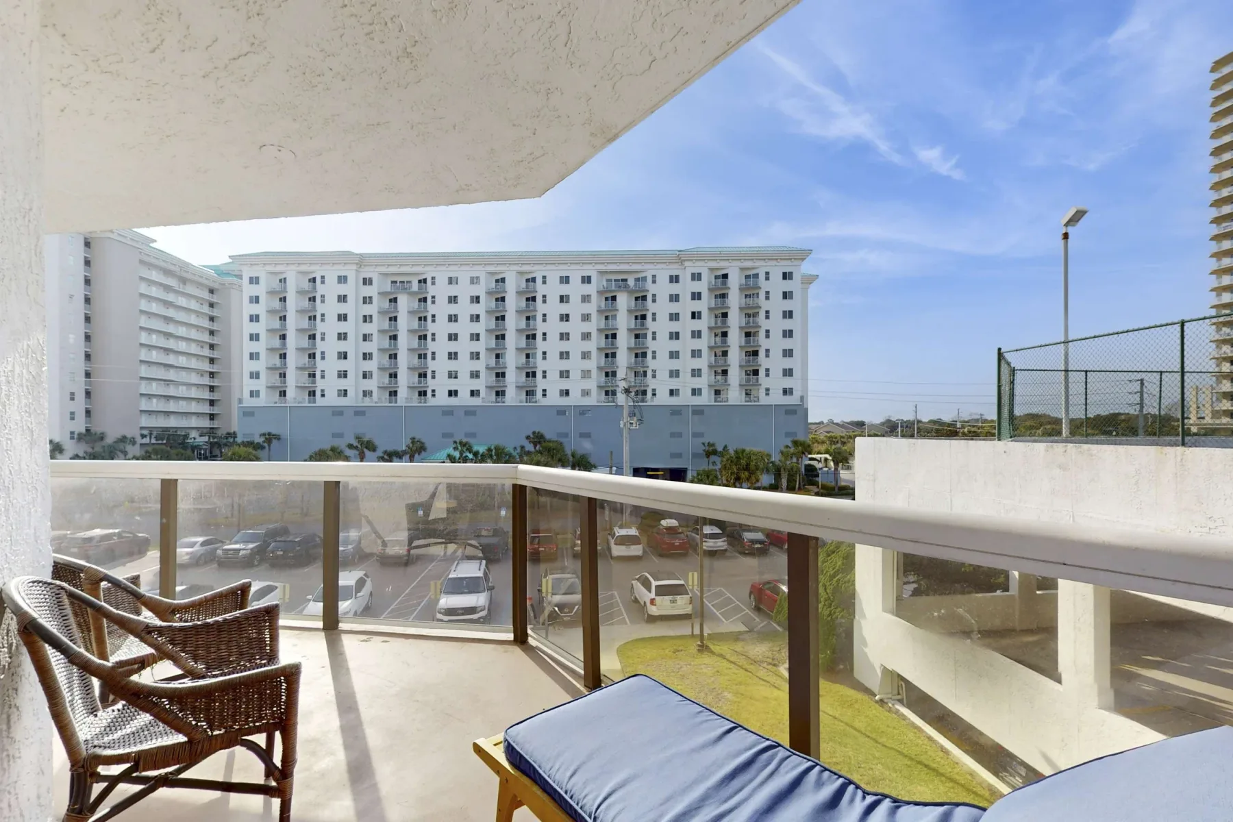 A balcony with seating and a cushioned lounger overlooks a large building.